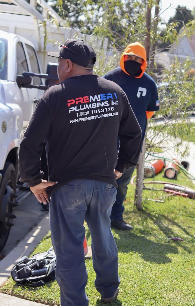 Two Premier 1 Plumbing technicians beside a branded service truck