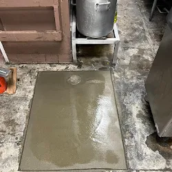 Fresh concrete patch poured over the completed sewer line repair at the restaurant