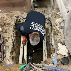 Premier 1 Plumbing crew member replacing a backed-up sewer line under a restaurant floor
